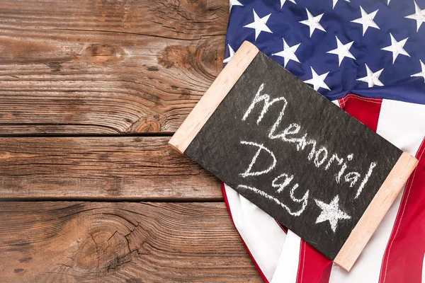 Chalkboard with text MEMORIAL DAY and USA flag on wooden background — Stock Photo, Image