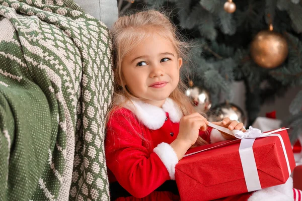 Cute little girl w stroju Mikołaja i z prezentem świątecznym w domu — Zdjęcie stockowe