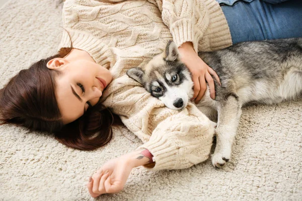 Young woman with funny husky puppy lying on floor at home — Stock Photo, Image