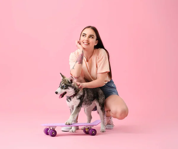 Mulher bonito com filhote de cachorro e skate husky engraçado no fundo de cor — Fotografia de Stock