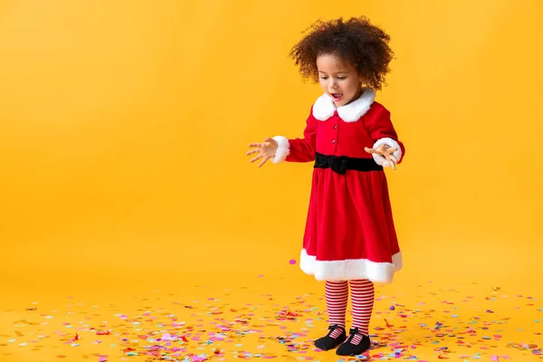Little African-American girl in Santa costume on color background