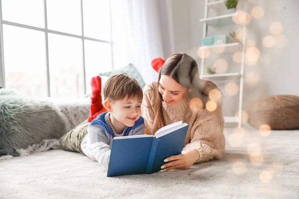 Cute little boy with mother reading book at home — Stockfoto