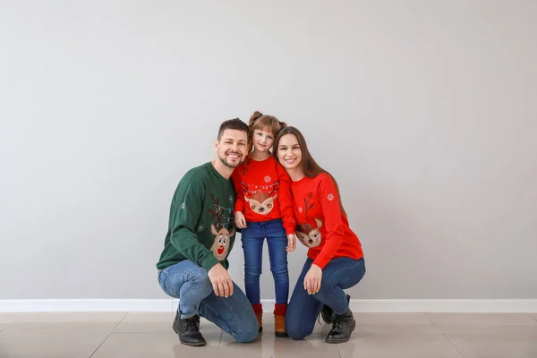 Щаслива сім'я в різдвяному одязі біля світлої стіни — стокове фото