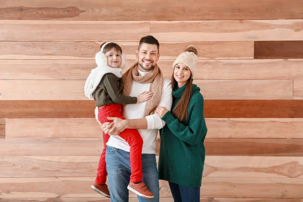 Happy family in winter clothes on wooden background — Stockfoto