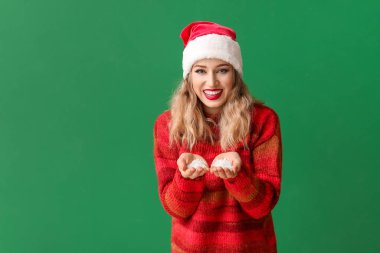 Noel Baba şapkalı güzel genç bir kadın ve arka planında kar var.