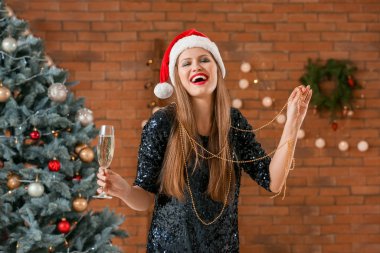 Evde Noel 'i şampanya ile kutlayan güzel genç bir kadın.