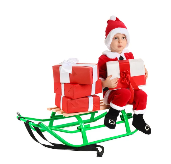 Cute little boy in Santa costume, with sledges and Christmas gifts on white background — Stockfoto