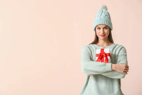 Щаслива молода жінка в зимовому одязі і з різдвяним подарунком на світлому фоні — стокове фото