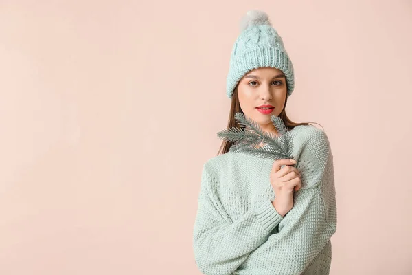 Jonge vrouw in winterkleding en met dennenboom tak op lichte achtergrond — Stockfoto