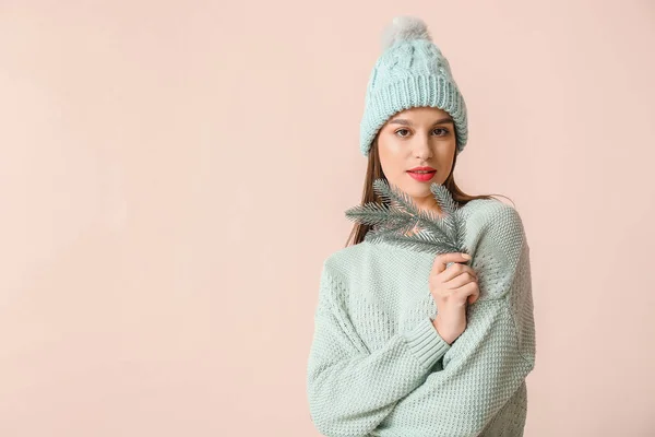 Jeune femme en vêtements d'hiver et avec branche de sapin sur fond clair — Photo