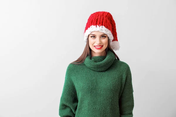 Belle jeune femme en chapeau de Père Noël sur fond clair — Photo