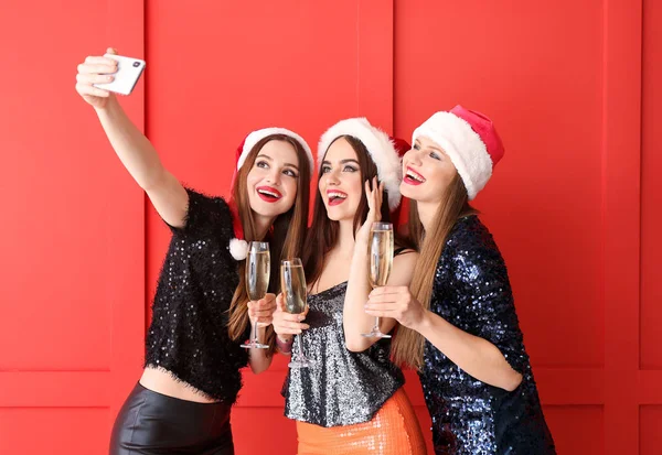 Beautiful young women with champagne taking selfie at Christmas party — Stock Photo, Image