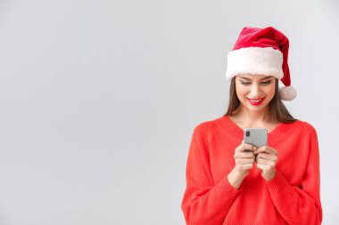 Noel Baba şapkalı ve cep telefonlu güzel bir kadın.