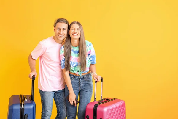 Pareja joven con maletas sobre fondo de color — Foto de Stock