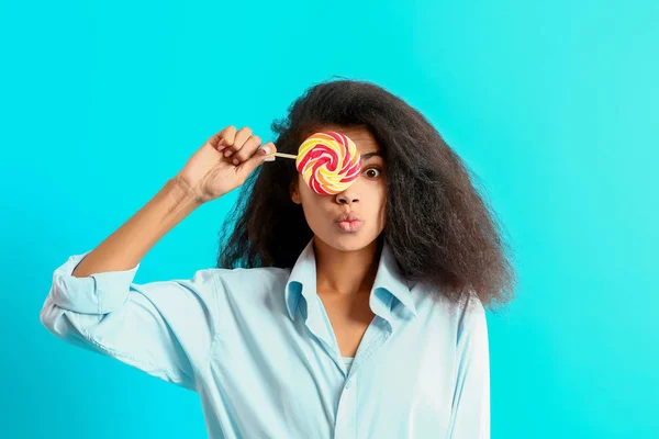 Verrast Afro-Amerikaanse vrouw met lekkere lolly op kleur achtergrond — Stockfoto