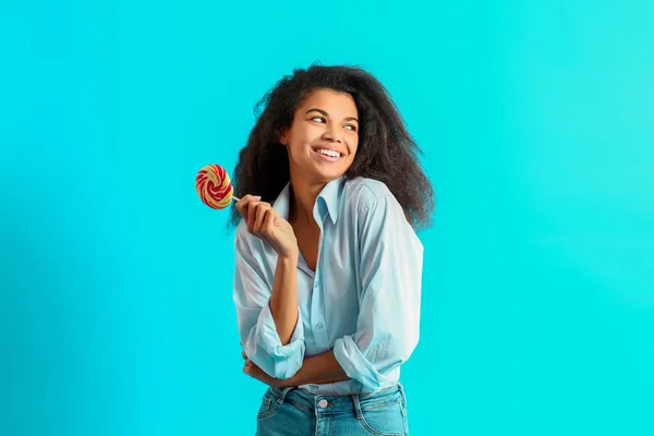 Mulher afro-americana feliz com pirulito saboroso no fundo de cor — Fotografia de Stock