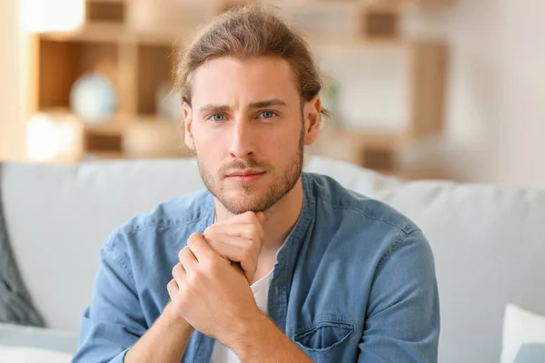 Handsome man sitting on sofa at home — Stock Photo, Image