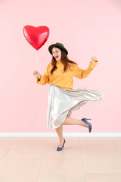 Schöne junge Frau mit herzförmigem Ballon in der Nähe der Farbwand — Stockfoto