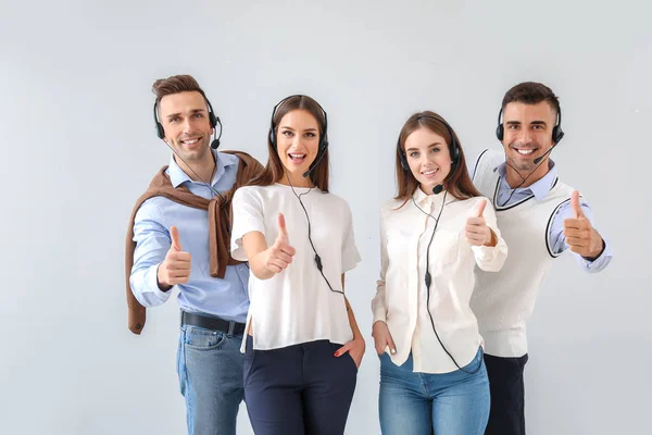 Team of technical support agents showing thumb-up gesture on white background