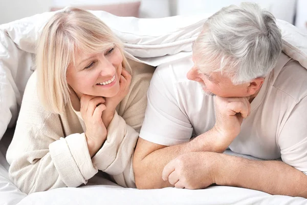 Happy mature couple lying under blanket in bed — Stock Photo, Image