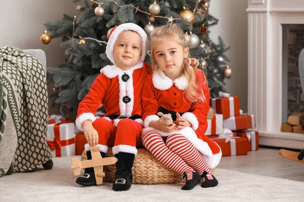 Niedliche kleine Kinder in Weihnachtsmannkostümen zu Hause an Heiligabend — Stockfoto