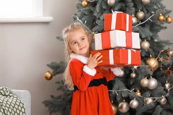 Cute little girl w stroju Mikołaja i prezenty świąteczne w domu — Zdjęcie stockowe