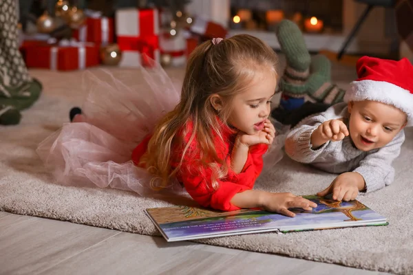 Słodkie małe dzieci czytające książkę w domu w Wigilię — Zdjęcie stockowe