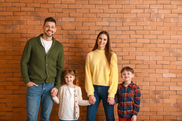 Happy family in winter clothes near brick wall