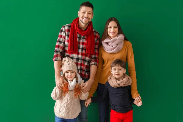 Happy family in winter clothes on color background — Stock Photo, Image