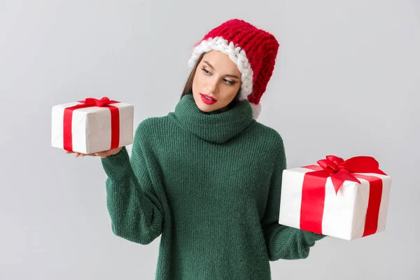 Bella giovane donna a Babbo Natale e con regali di Natale su sfondo chiaro — Foto Stock
