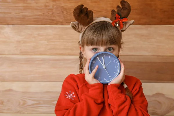 Κοριτσάκι με ξυπνητήρι σε ξύλινο φόντο. Χριστούγεννα αντίστροφη μέτρηση έννοια — Φωτογραφία Αρχείου