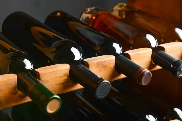 Wooden holder with bottles of wine in cellar — Stock Photo, Image