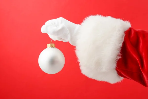 Mano de Santa con bola de Navidad sobre fondo de color — Foto de Stock