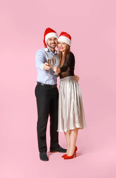 산타클로스 모자를 쓰고 색채가 있는 샴페인 잔을 든 행복 한 부부 — 스톡 사진