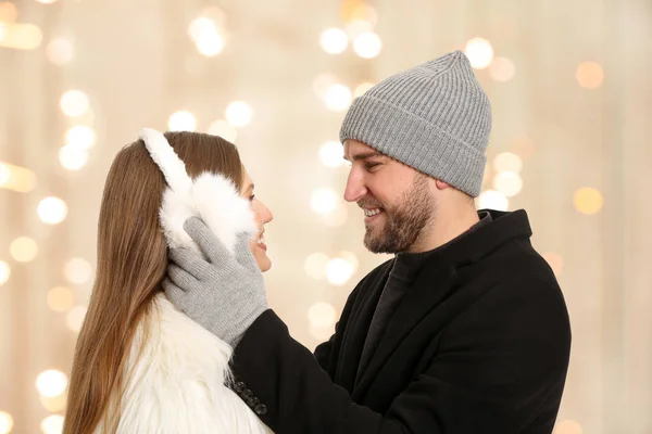 Portrait of happy couple in winter clothes against blurred Christmas lights — Stock Photo, Image