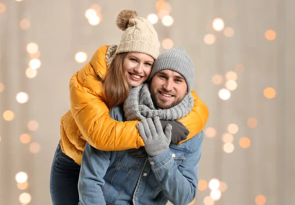 Retrato de pareja feliz en ropa de invierno contra las luces borrosas de Navidad — Foto de Stock
