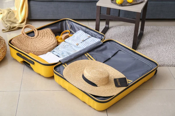 Open suitcase with packed clothes on floor at home