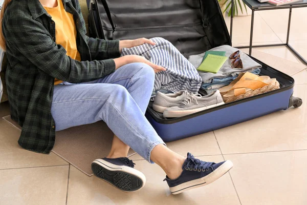 Young woman packing luggage at home