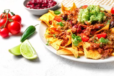 Plate with tasty chili con carne and nachos on table clipart