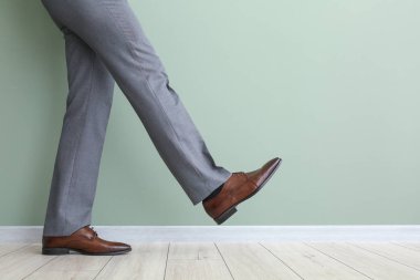 Renkli duvarın yanında şık ayakkabılı genç adam.