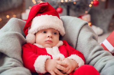 Evde Noel Baba kostümlü şirin bir bebek var.