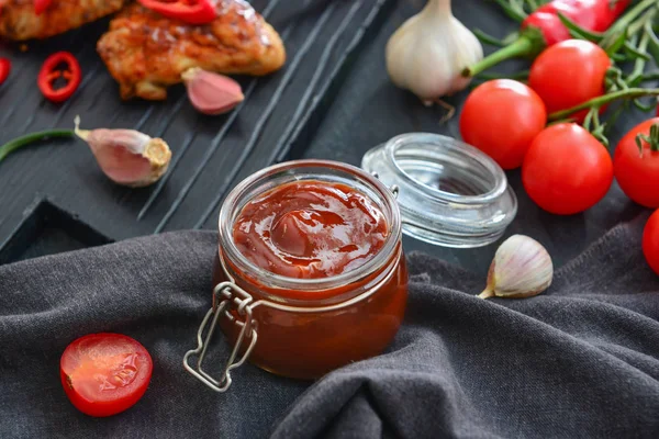 Jar with barbecue sauce on dark table — Stock Photo, Image