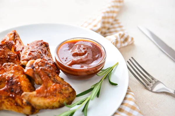 Bord met lekkere gebakken kippenvleugels en barbecuesaus op witte tafel — Stockfoto
