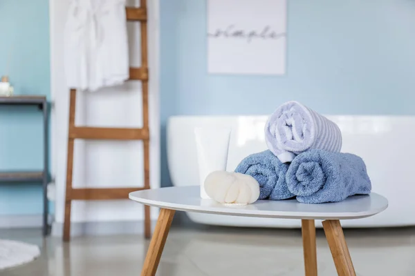 Clean towels with cosmetics and bast wisp on table in bathroom