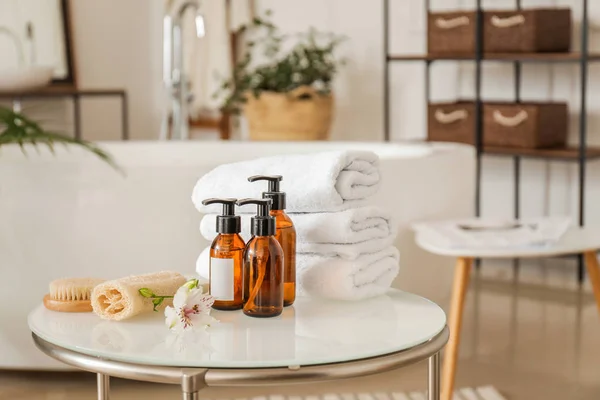 Clean towels with cosmetics and supplies on table in bathroom — Stock Photo, Image