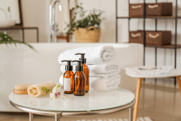 Clean towels with cosmetics and supplies on table in bathroom