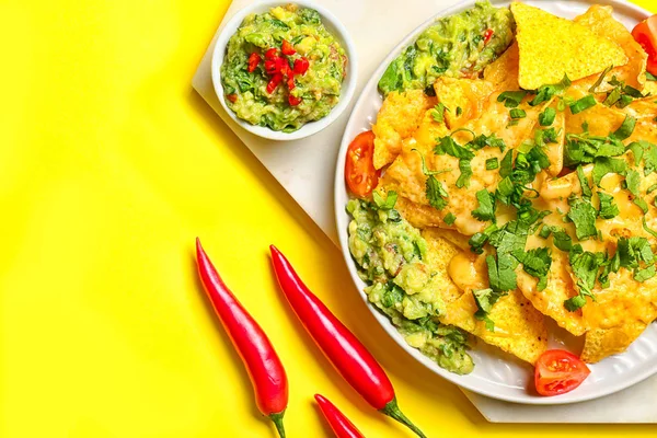 Board with tasty nachos and guacamole on color background — Stock Photo, Image