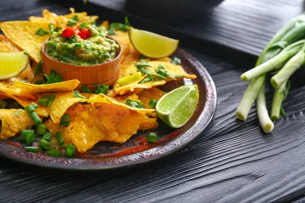 Teller mit leckeren Nachos und Guacamole auf dunklem Tisch — Stockfoto