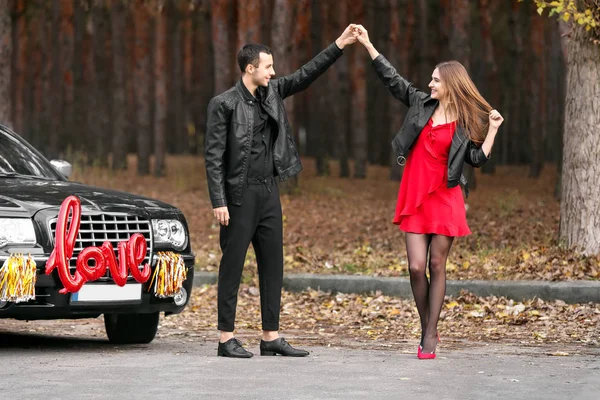 Gelukkig jong stel dansend in de buurt van auto buiten. Valentijnsdag — Stockfoto