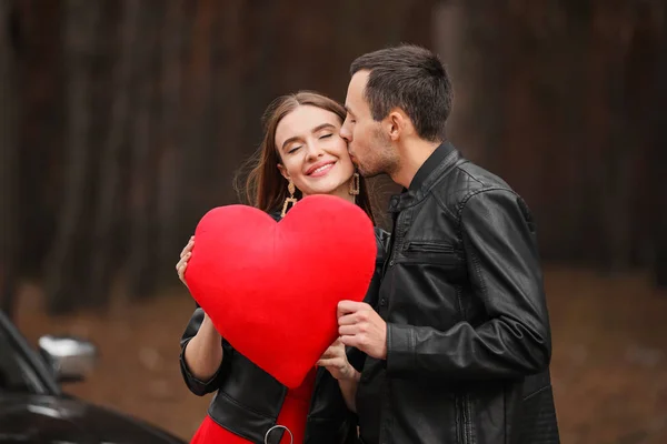 Jovem casal feliz com coração vermelho ao ar livre. Celebração do Dia dos Namorados — Fotografia de Stock